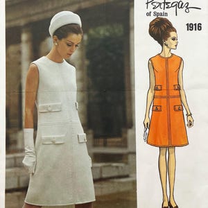 May include: A sewing pattern envelope for a Pertegaz of Spain dress, style 1916. The cover features a photograph of a sleeveless white dress with four buttoned pockets and a matching pillbox hat, alongside an orange illustration of the same dress.