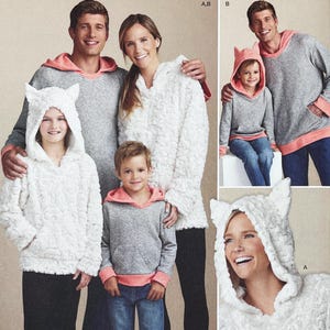 Puede incluir: Una familia con sudaderas grises a juego con ribetes color coral y chaquetas con capucha blancas texturizadas. Las chaquetas de los niños tienen detalles de orejas de gato en la capucha. Los adultos sonríen.