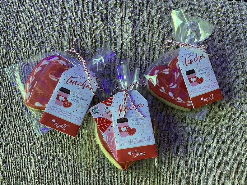May include: Three heart-shaped cookies decorated with white swirls and a red glaze. Each cookie is packaged in a clear plastic bag with a gift tag that reads "If you've got a teacher who's probably wants lots of coffee... Happy Valentine's Day". The tags are signed with the names "Wyatt", "Aven", and "Wyatt".