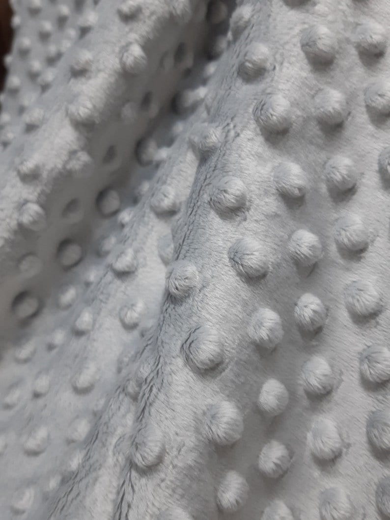 May include: Close-up of a soft, gray fabric with a textured, dotted pattern. The fabric is plush and has a subtle sheen.