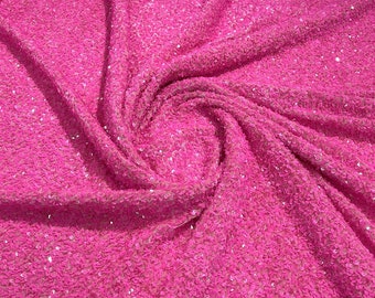 May include: A close-up of a pink fabric with sequins. The fabric is folded and has a soft, shimmery texture.