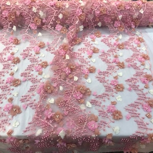 May include: Pink floral lace fabric with 3D flowers and pearl beads. The fabric has a delicate, feminine look and is perfect for adding a touch of elegance to any project.
