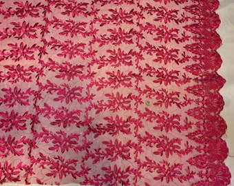 May include: Burgundy red lace fabric with a floral pattern. The lace has a delicate, intricate design with small, beaded accents.