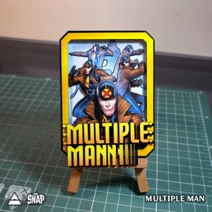 May include: A yellow and gold card with a comic book image of multiple men in blue and yellow costumes. The card has the text "MULTIPLE MAN" in bold, yellow letters.