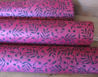 Puede incluir: Tres rollos de papel decorativo con un vibrante fondo fucsia. El papel está estampado con un diseño repetitivo de ramas de olivo azul oscuro y pequeños círculos. Los rollos están apilados horizontalmente, mostrando el patrón.