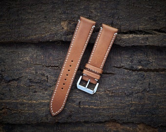 May include: Two brown leather watch straps with white stitching. The straps have silver buckles.