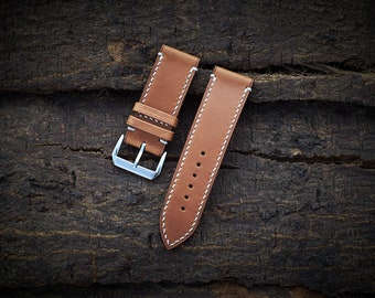 May include: Two brown leather watch straps with white stitching. The straps have silver buckles.