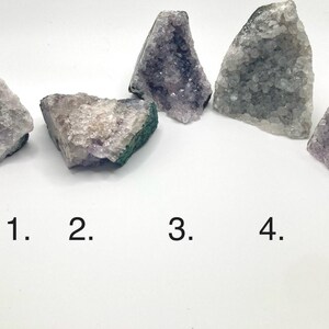 May include: Five amethyst crystal clusters of varying sizes and shapes. The crystals are a light purple color with some white and green inclusions. The crystals are numbered 1 through 5.