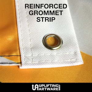 May include: Close-up of a white fabric flag with a reinforced grommet strip. The grommet is made of metal and has a gold finish. The text "REINFORCED GROMMET STRIP" is printed in black on the flag.