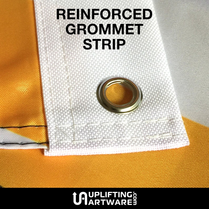 May include: Close-up of a white fabric flag with a reinforced grommet strip. The grommet is made of metal and has a gold finish. The text "REINFORCED GROMMET STRIP" is printed in black on the flag.