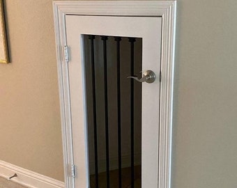 Puede incluir: Puerta blanca con una reja de metal negro y un pomo de puerta plateado. La puerta está enmarcada con moldura blanca.