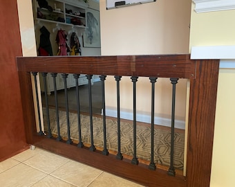 May include: A wooden gate with black metal spindles. The gate is stained a dark brown color and has a simple design.