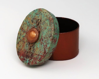 May include: A small, round, teal and copper trinket box with a textured lid. The lid has a copper accent and a wire design.