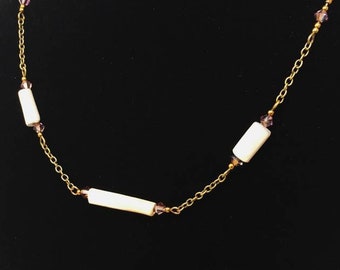 May include: A gold chain necklace with three white rectangular beads and small purple beads.