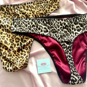Può includere: Due paia di biancheria intima con motivo leopardato nei toni del marrone, nero e beige. Un paio mostra la fodera interna in un colore bordeaux intenso. È presente un piccolo cartoncino quadrato azzurro con il testo MARINE LACE SPACE.