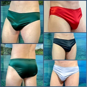 Puede incluir: Un collage de ropa interior de sat&eacute;n en varios colores: verde esmeralda, rojo, negro y blanco. Cada par tiene un corte de cintura baja con un ribete contrastante a lo largo de la cintura y las aberturas de las piernas. La tela tiene un ligero brillo.