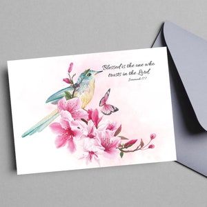 May include: A watercolor painting of a blue bird perched on a branch of pink cherry blossoms. A butterfly is flying nearby. The quote "Blessed is the one who trusts in the Lord. Jeremiah 17:7" is written in white text on a pink background.