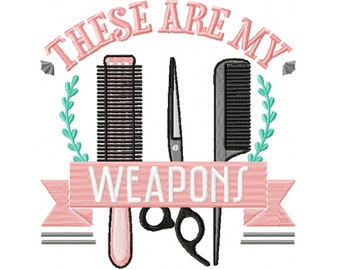 May include: An embroidered design featuring hairstyling tools: a comb, scissors, and a brush. The text "THESE ARE MY WEAPONS" is displayed on a pink banner. The design includes a teal leafy accent and is set against a white background.