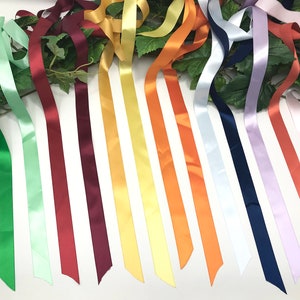 May include: Assortment of 15 satin ribbon spools in various colors, including white, green, light green, red, burgundy, yellow, orange, and lavender.