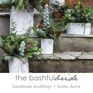 May include: Four white birch bark planters with green plants and greenery on a set of stone steps. The planters are arranged in a staggered pattern. The text "the bashful bride" and "handmade weddings + home decor" is at the bottom of the image.