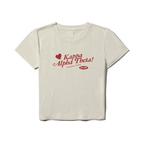 Może przedstawiać: Kremowa koszulka z czerwonym sercem i napisem "Kappa Alpha Theta! Inspiring Women Est. 1870"