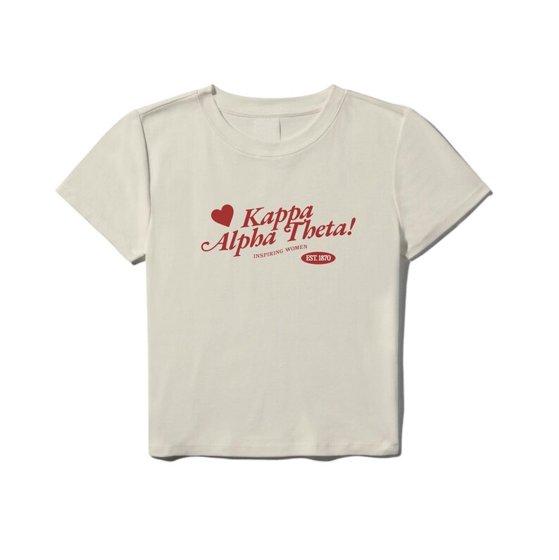 Może przedstawiać: Kremowa koszulka z czerwonym sercem i napisem "Kappa Alpha Theta! Inspiring Women Est. 1870"