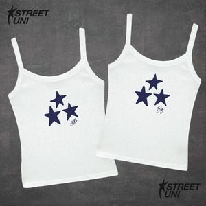 May include: Two white tank tops with navy blue star graphics. One top says "Little" and the other says "Big". The tops have thin straps and are from Street Uni.