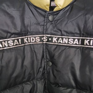 May include: Black puffer jacket with a gold lining and a silver and black "KANSAI KIDS" logo.