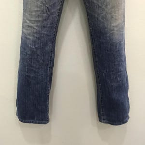 Op de afbeelding: Verbleekte blauwe denim jeans met een rechte pijp. De jeans hebben een versleten uiterlijk met lichtere plekken op de dijen en knie&euml;n. De denim is van gemiddeld gewicht en heeft een klassiek ontwerp met vijf zakken.