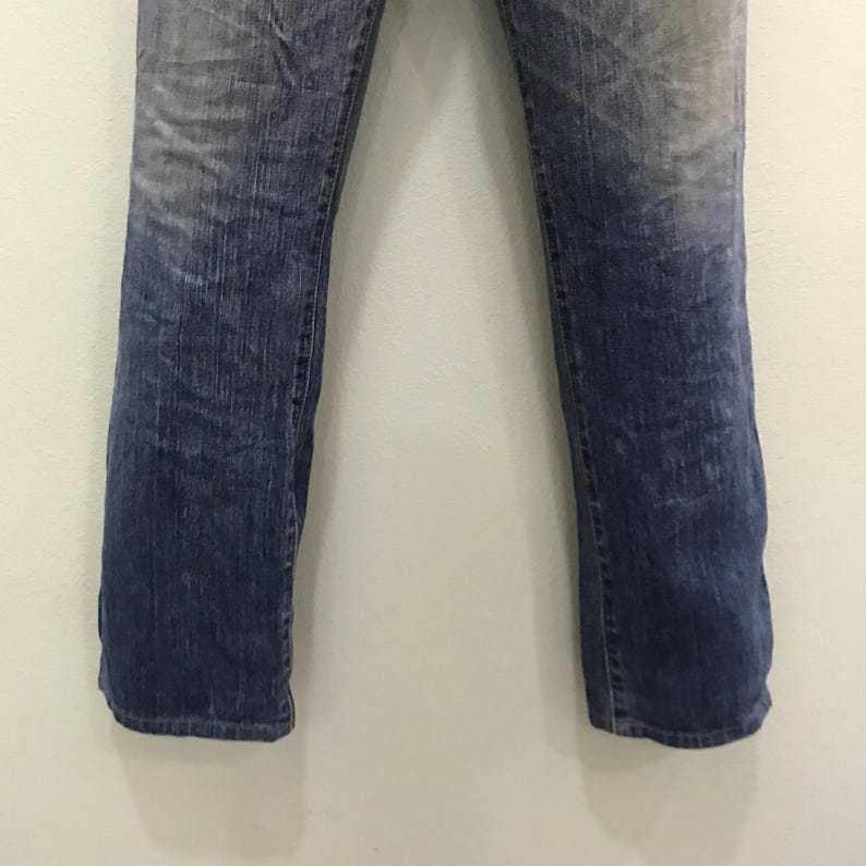 Op de afbeelding: Verbleekte blauwe denim jeans met een rechte pijp. De jeans hebben een versleten uiterlijk met lichtere plekken op de dijen en knie&euml;n. De denim is van gemiddeld gewicht en heeft een klassiek ontwerp met vijf zakken.