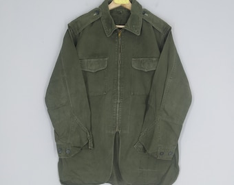 May include: A green utility jacket with a zipper closure and two large flap pockets on the front. The jacket has a collared neckline and long sleeves.