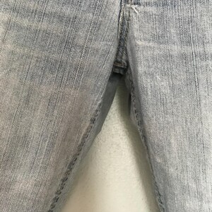 K&ouml;nnte beinhalten: Nahaufnahme einer hellblauen Jeans. Die Jeans zeigt die Vorderseite der Hose mit der Naht und dem Bereich, in dem sich der Rei&szlig;verschluss befinden w&uuml;rde. Der Denim hat ein verwaschenes, abgenutztes Aussehen.