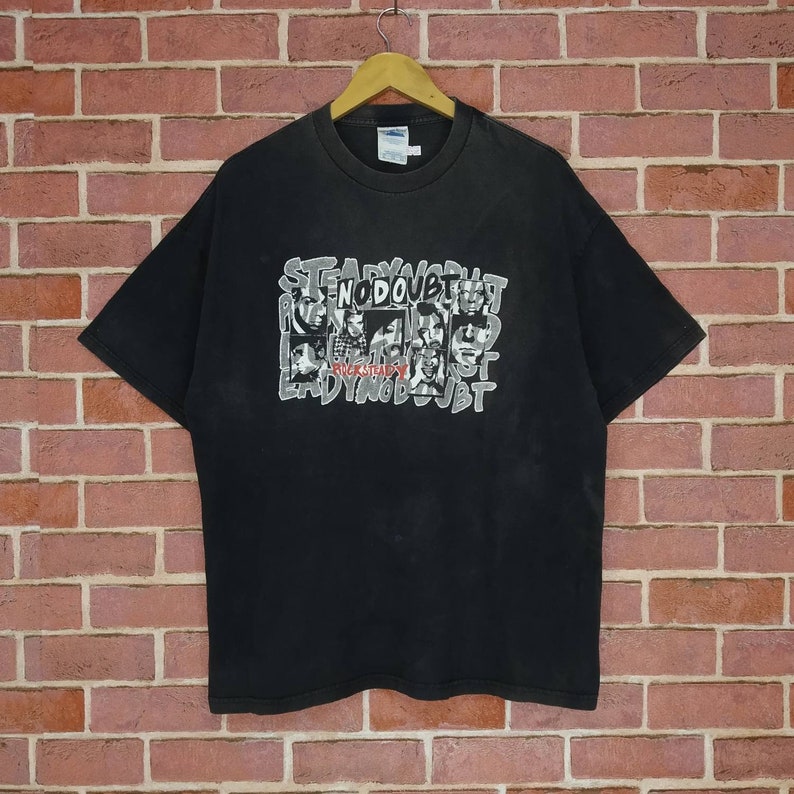 May include: Black t-shirt with a graphic print of the band No Doubt. The print features the band members' faces in black and white, with the band's name in white and red lettering.