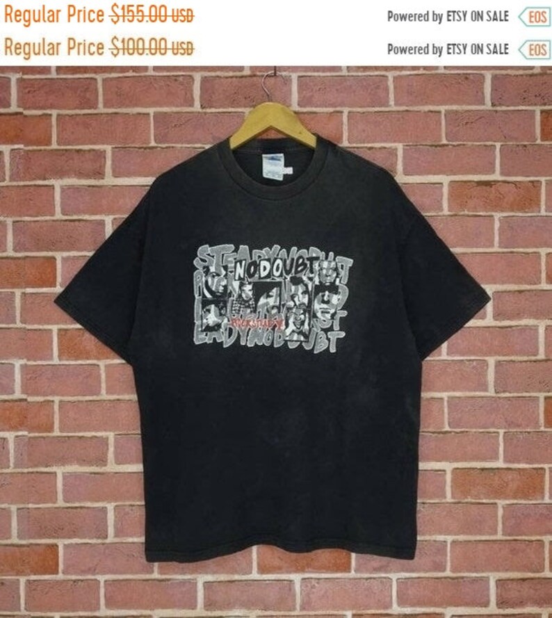 May include: Black t-shirt with a white graphic print of the band No Doubt. The graphic features the band members' faces in a collage style with the band's name written in a stylized font.