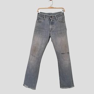 K&ouml;nnte beinhalten: Hellblaue Jeans aus Denim mit Used-Look und einem Riss am rechten Knie. Die Jeans h&auml;ngen an einem Holzb&uuml;gel. Die Jeans haben ein klassisches F&uuml;nf-Taschen-Design.