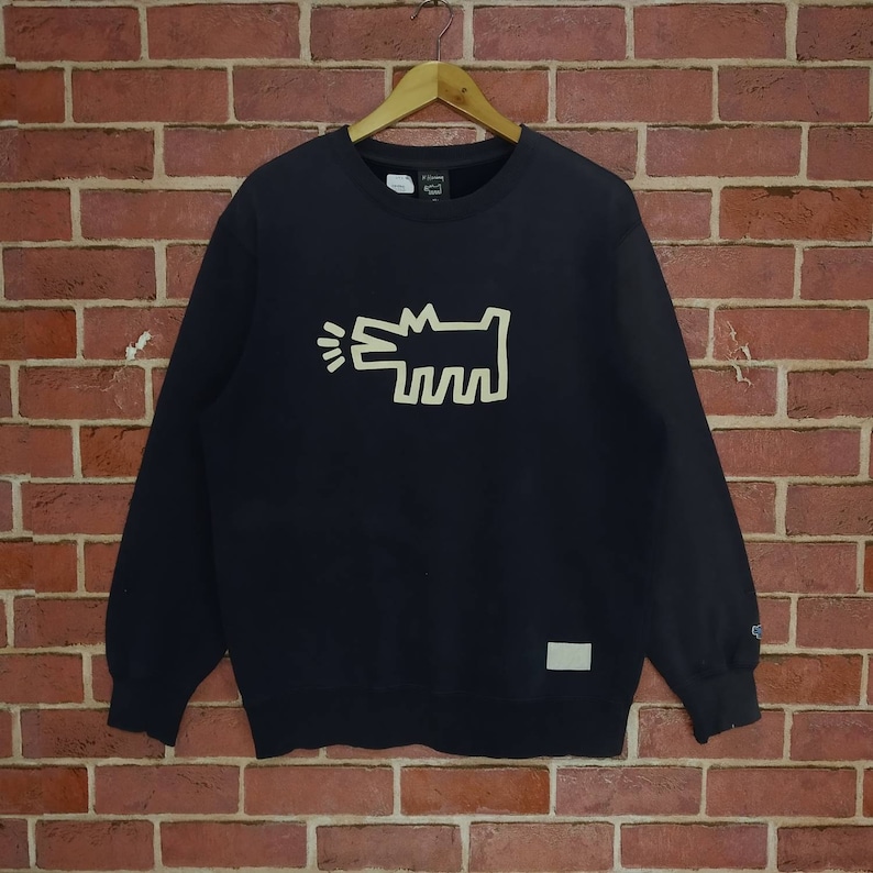 May include: Black sweatshirt with a cream-colored graphic of a barking dog. The sweatshirt has a crew neck and long sleeves.