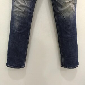 May include: Blue denim jeans with a faded wash and distressed details. The jeans have a classic five-pocket design and a straight leg fit. The denim has a worn appearance.
