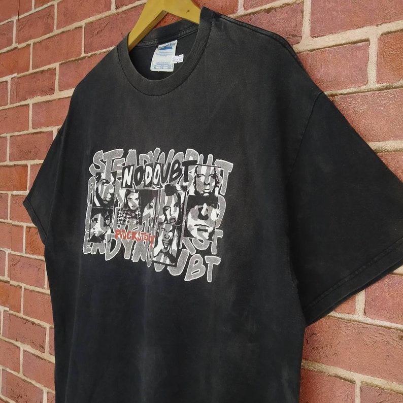 May include: Black t-shirt with a faded graphic print of the band No Doubt. The graphic features the band members' faces and the words "Rock Steady" and "No Doubt".