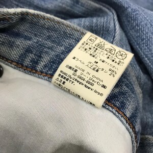 May include: Close-up of a light blue denim garment with a white interior. A rectangular tag is attached, displaying Japanese text and care symbols. The tag indicates the garment is made in China and lists the fabric composition.