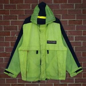 May include: A bright green and black hooded jacket with a reflective strip on the hood and the word "HILFIGER" printed on the front.