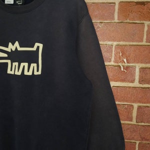 May include: Black sweatshirt with a yellow graphic of a dog on the front.