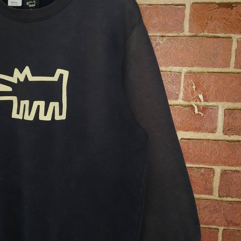 May include: Black sweatshirt with a yellow graphic of a dog on the front.