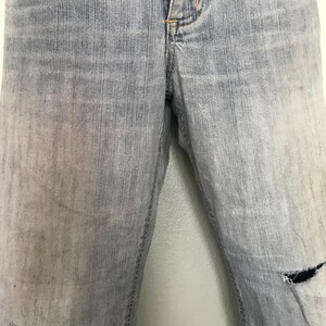K&ouml;nnte beinhalten: Hellblaue Jeans mit einem Used-Look. Die Jeans haben einen verblichenen Waschton und ein gerissenes Knie. Der Stoff weist Gebrauchsspuren auf, was ihnen einen Vintage-Look verleiht. Die Jeans sind ein klassischer Stil.