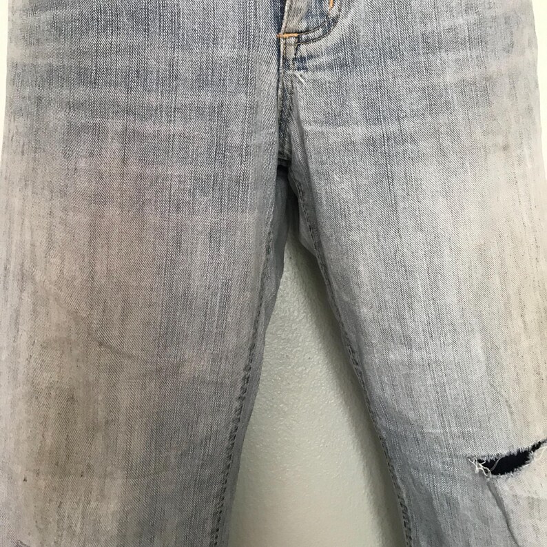 K&ouml;nnte beinhalten: Hellblaue Jeans mit einem Used-Look. Die Jeans haben einen verblichenen Waschton und ein gerissenes Knie. Der Stoff weist Gebrauchsspuren auf, was ihnen einen Vintage-Look verleiht. Die Jeans sind ein klassischer Stil.