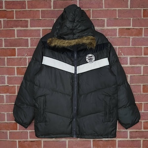 Może przedstawiać: Czarna kurtka puchowa z białym paskiem i kapturem wyłożonym sztucznym futrem. Kurtka zapinana na zamek błyskawiczny z naszywką z logo "World Famous Tag".