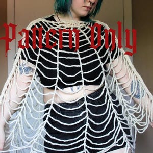 May include: Cream-colored, open-weave crochet shawl with a spiderweb design. The shawl is draped over a black top and black shorts. The text "Pattern Only" is displayed in red gothic font across the top of the image.