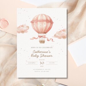 May include: A baby shower invitation featuring a pink hot air balloon with a basket, clouds, and stars. The invitation text reads "Join us to celebrate Catherine's Baby Shower" with the date, time, and RSVP information.