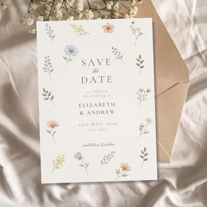 Può includere: Un biglietto di annuncio di matrimonio con il testo "SAVE the DATE" e i nomi "ELIZABETH & ANDREW" circondati da illustrazioni floreali ad acquerello. La data è il 26 maggio 2026. Include una busta beige.