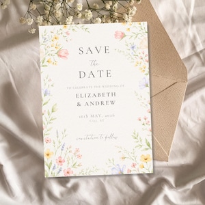 Può includere: Un invito di nozze floreale con il testo "Save the Date" e i nomi "Elizabeth & Andrew". L'invito è decorato con fiori ad acquerello nei toni del rosa, giallo e blu. È visibile una busta abbinata.