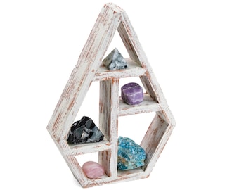 Pode incluir: Prateleira geométrica de madeira branca com cinco prateleiras, exibindo vários cristais e pedras preciosas, incluindo uma ponta de quartzo transparente, ametista, obsidiana preta, apatita azul e quartzo rosa.
